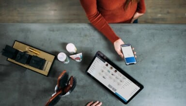 person holding smartphone beside tablet computer