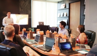 man standing in front of people sitting beside table with laptop computers