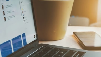 white laptop computer turned on beside brown paper cup