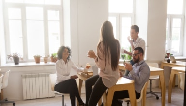 smiling employees enjoying pizza having shared lunch break in of