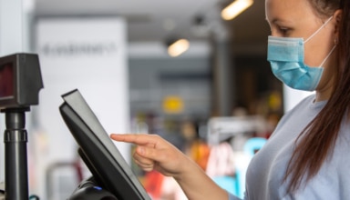 young saleswoman doing process payment on the touchscreen pos, counting sale in the cash register, finance concept