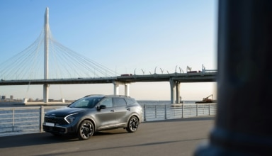 a silver car driving down a street next to a bridge