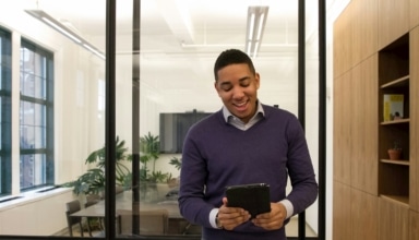 a man standing in an office looking at a tablet