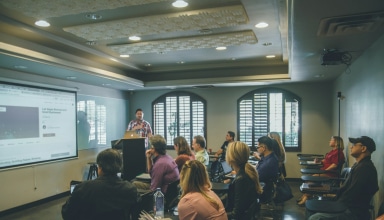 a group of people in a room with a projector screen