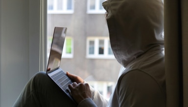 a person sitting on a window sill using a laptop
