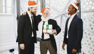Businessmen in suits celebrating Christmas with gifts in an office setting.